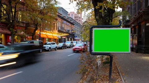 A billboard with a green screen on a background of autumn city traffic with long Stock Footage 99172007
