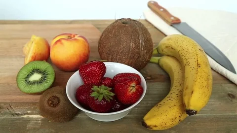 Billet for fruit cocktail on a cutting board bananas, strawberries, peach. Stock Footage 77703473