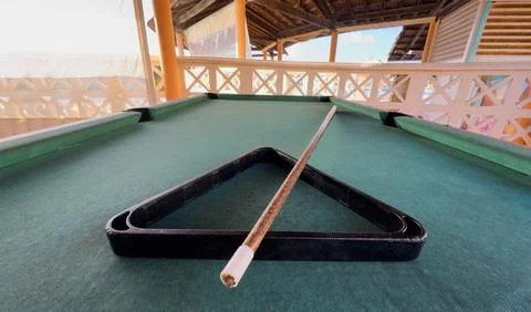 Billiard balls arranged in a triangle and a cue stick are lying on a green .. Stock Photos