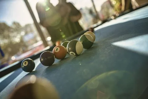 Billiard balls scattered on pool table in sunny game room Stock Photos