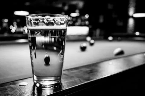 In a billiard parlor on the rail of a pool table is a glass with a beer Stock Photos