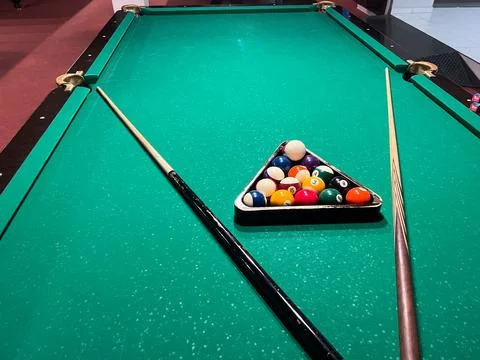 Billiard table is set up with a triangle of balls and cues positioned on ei.. Stock-Fotos