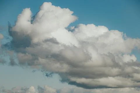 Billowing white cumulus clouds with layered forms against a clear blue sky,.. Stock Photos