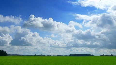 Billowy clouds drift over green landscape in seamless loop Stock Footage 79015273