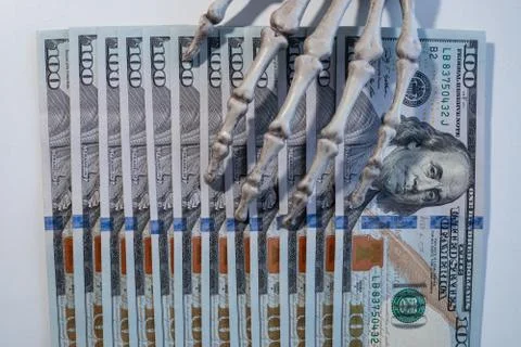 Bills $ 100 are on hand of the skeleton. Illustrazione stock