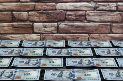 Bills of one hundred dollars on a table of dark glass near a brick wall Stock Photos