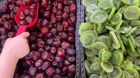 A bin of glossy red dried cherries on the left and vibrant green dried kiwi Stock Footage 311649185