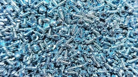 A bin is overflowing with many small, silver screws, ready for use in const.. Stock Photos