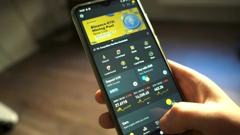 Binance crypto currency trading app. Young male trader buys Bitcoin on his Video stock 143157650