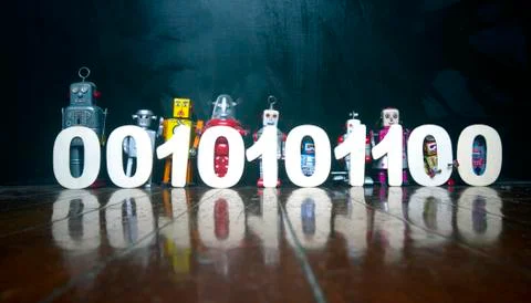 Binary cod held by a line of vintage robot toys on a wooden floor Foto stock