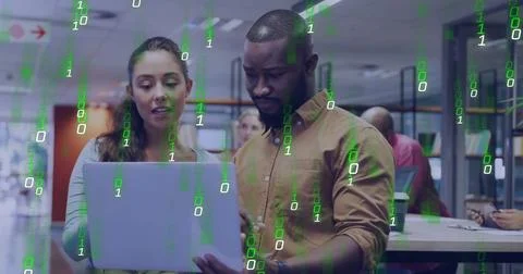 Binary code image over diverse business people working on laptop in office 写真素材