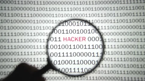 Binary code with a red label hacker is viewed with a magnifying glass. 스톡 동영상 144633438