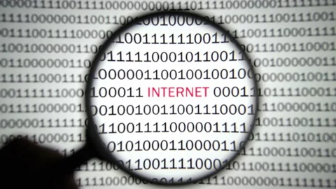 Binary code with a red label Internet is viewed with a magnifying glass. 스톡 동영상 144633319