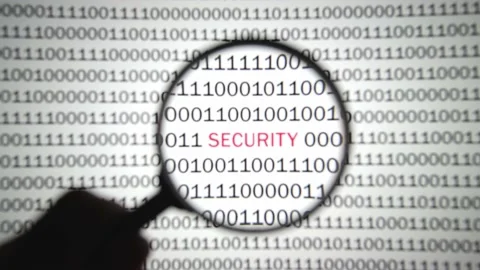 Binary code with a red label security is viewed with a magnifying glass. 스톡 동영상 144633207