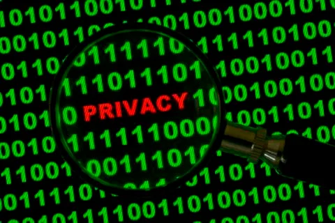 Binary code with the word Privacy viewed through a magnifying glass 写真素材