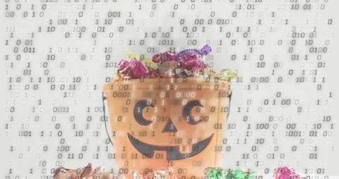Binary digits appearing over orange pumpkin bucket of candy, wrappers tumbling Video stock 317772423