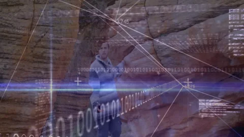 Binary tech overlay fading revealing canyon walls as man stepping from boulder Stock Footage 312038345