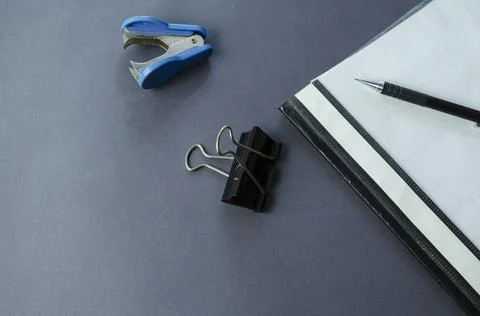 Binder folder, binder clip, staple remover and pencil on a gray table. Stock Photos