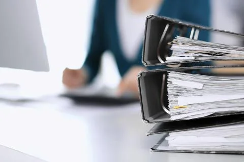 Binders with papers are waiting to be processed by business woman or bookkeeper Stock Photos