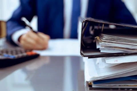 Binders with papers waiting to be processed with businessman or bookkeeper back Stockfoto's