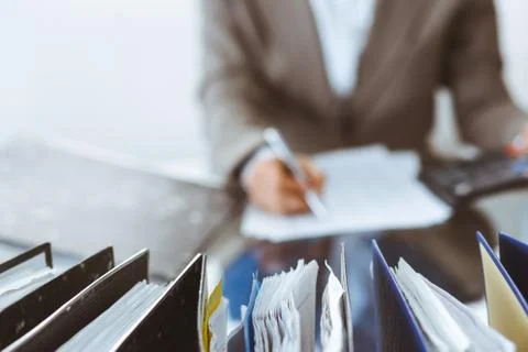 Binders of papers waiting to process by bookkeeper woman or financial inspector Фото