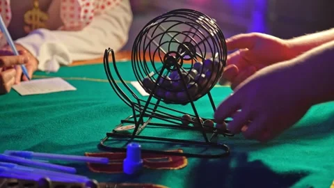 Bingo Game Croupier Picking Random Number Ball from Metal Wheel Cage Roller Stock Footage 285673720