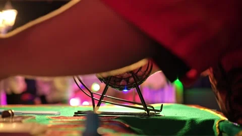Bingo Game Croupier Picking Random Number Ball from Metal Wheel Cage Roller Stock Footage 285971734