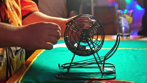 Bingo Game Croupier Picking Random Number Ball from Metal Wheel Cage Roller Stock Footage 285974000