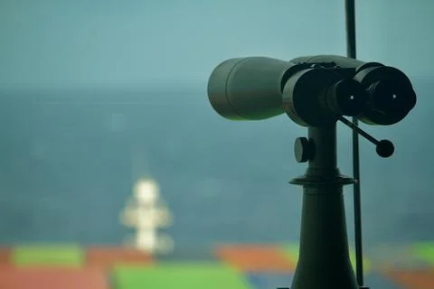 A binocular fixed on the bridge of a container ship underway at sea in the .. Stock Photos
