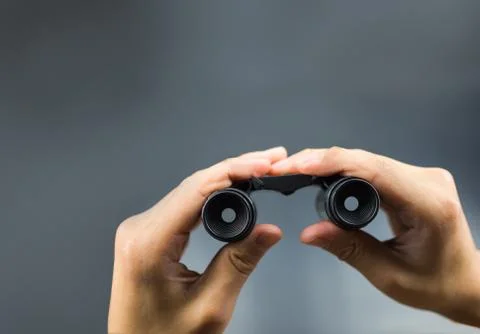 Binocular on hand holding with grey background Stock Photos