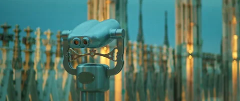 Binocular viewer overlooking spires on Milan cathedral rooftop at twilight Stock Footage 313702980