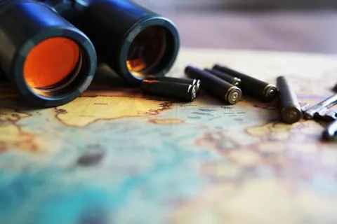 Binoculars and reflection in lenses. Map and shells background. Foto stock