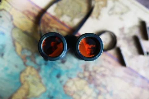 Binoculars and reflection in lenses. Map and shells background. Foto stock