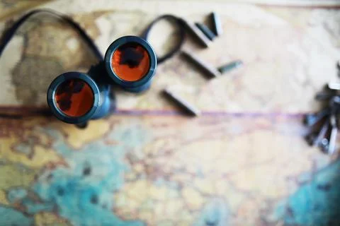 Binoculars and reflection in lenses. Map and shells background. Foto stock
