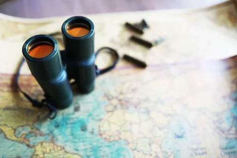 Binoculars and reflection in lenses. Map and shells background. Foto stock