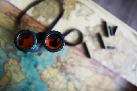 Binoculars and reflection in lenses. Map and shells background. Foto stock