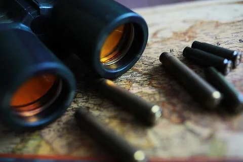 Binoculars and reflection in lenses. Map and shells background. Foto stock