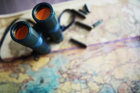 Binoculars and reflection in lenses. Map and shells background. Foto stock