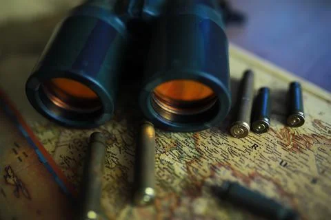 Binoculars and reflection in lenses. Map and shells background. Foto stock