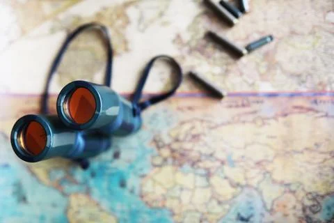 Binoculars and reflection in lenses. Map and shells background. Foto stock