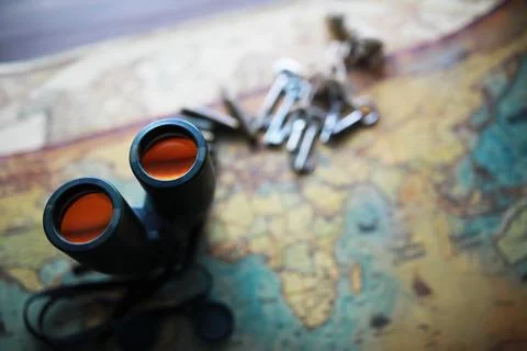 Binoculars and reflection in lenses. Map and shells background. Foto stock