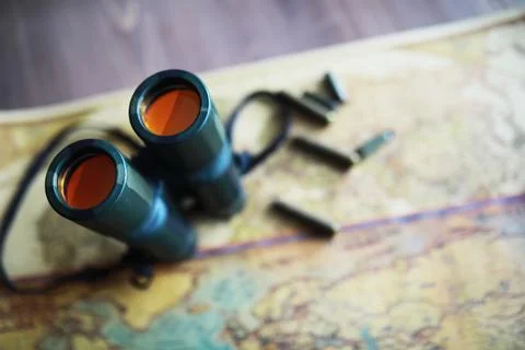 Binoculars and reflection in lenses. Map and shells background. Foto stock