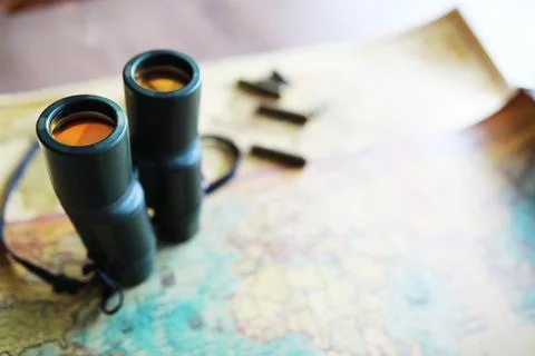 Binoculars and reflection in lenses. Map and shells background. Foto stock