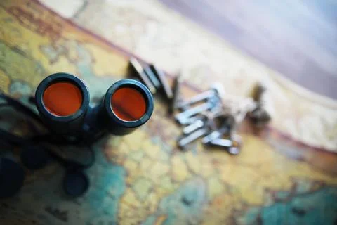 Binoculars and reflection in lenses. Map and shells background. Foto stock