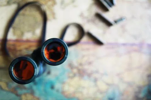 Binoculars and reflection in lenses. Map and shells background. Foto stock