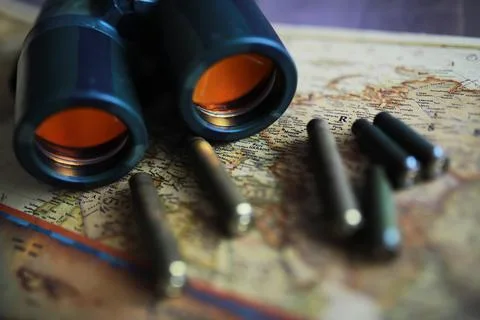 Binoculars and reflection in lenses. Map and shells background. Foto stock