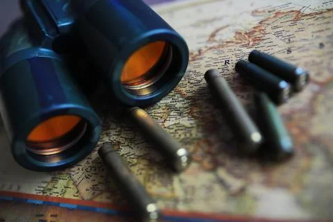 Binoculars and reflection in lenses. Map and shells background. Foto stock