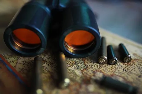 Binoculars and reflection in lenses. Map and shells background. Foto stock