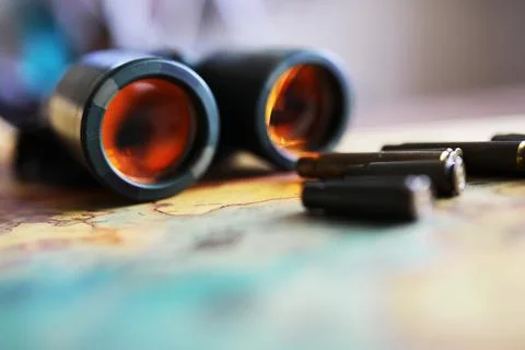 Binoculars and reflection in lenses. Map and shells background. Foto stock