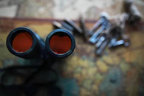 Binoculars and reflection in lenses. Map and shells background. Foto stock